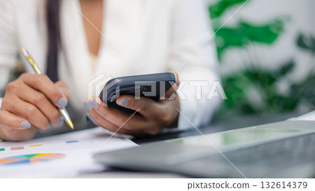 Businesswoman using smartphone and analyzing financial report for digital business productivity concept Businesswoman using smartphone and analyzing financial report for digital business productivity concept 132614379