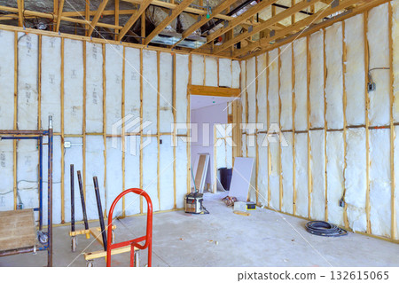 Construction work takes place in spacious room with insulation tools scattered around on floor. Construction work takes place in spacious room with insulation tools scattered around on floor. 132615065