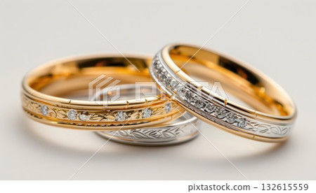 Close up of two wedding rings on a white surface, made of metal and gemstone Close up of two wedding rings on a white surface, made of metal and gemstone 132615559