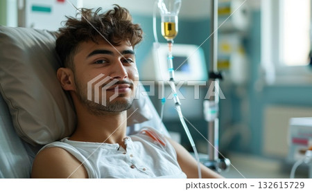 A young man in a hospital bed with an IV, smiling and gesturing happily 132615729