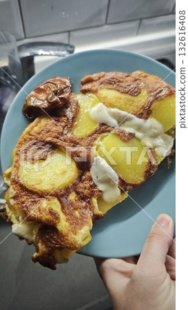 Homemade fried potatoes with eggs and melted cheese served on a blue plate. The image represents the concept of simple home cooking and hearty comfort food 132616408