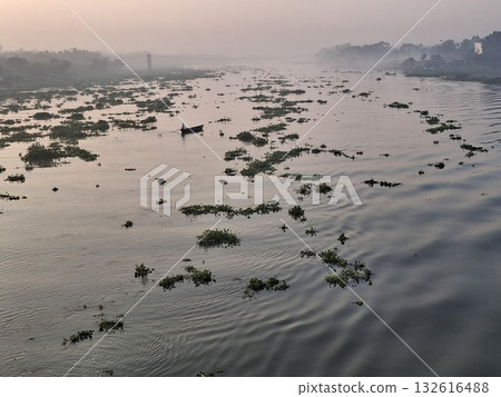 Aerial view of a wide, shallow river with scattered vegetation and sandbars under a hazy sky Aerial view of a wide, shallow river with scattered vegetation and sandbars under a hazy sky 132616488