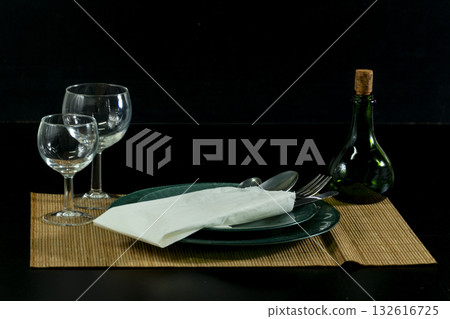 A table with a green plate, fork, knife, and two wine glasses A table with a green plate, fork, knife, and two wine glasses 132616725