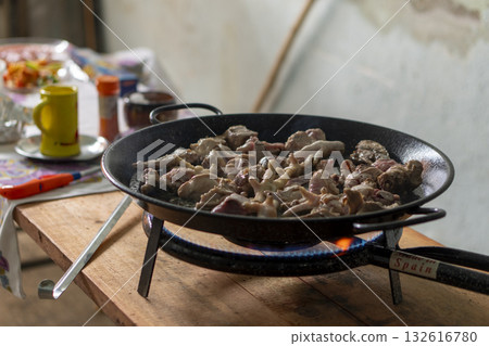 A pan of meat is cooking on a stove A pan of meat is cooking on a stove 132616780