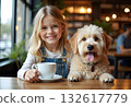 Pretty smiling girl with small dog in her arms sitting at table in restaurant with cup of coffee. Woman with dark hair in cafe with pet on dark background. 132617779