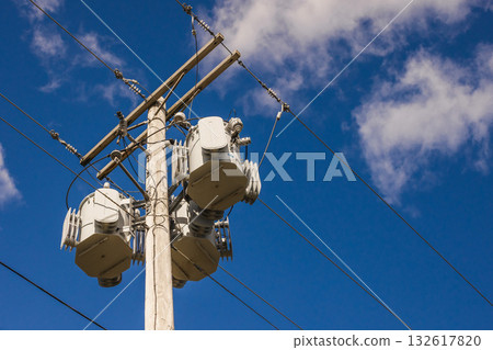 Wooden utility pole with multiple electrical transformers and power lines against a clear blue sky in the USA Wooden utility pole with multiple electrical transformers and power lines against a clear blue sky in the USA 132617820