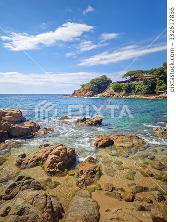Sunny coastal view of Cala Bona, Sant Francesc bay in Blanes, Costa Brava, Spain. A picturesque cove famous for its golden sand, crystal-clear water, and stunning rocky cliffs with pine trees Sunny coastal view of Cala Bona, Sant Francesc bay in Blanes, Costa Brava, Spain. A picturesque cove famous for its golden sand, crystal-clear water, and stunning rocky cliffs with pine trees 132617836