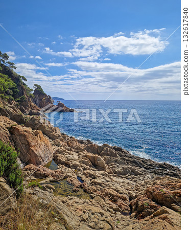 Sunny coastal view with sea waves gently crashing against the rocky shoreline. Beautiful turquoise water coastline of Cala sant Francesc Beach in Blanes (Costa Brava), Spain 132617840