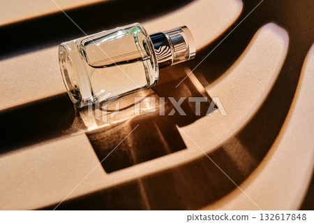 Is the perfume spray bottle lying on a beige background with shadow stripes. Is the perfume spray bottle lying on a beige background with shadow stripes. 132617848