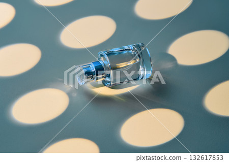 A bottle of perfume on a blue background in a yellow oval. A bottle of perfume on a blue background in a yellow oval. 132617853