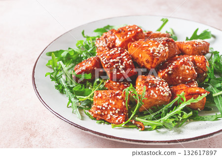 fried salmon slices, teriyaki with sesame seeds, with arugula salad, top view, 132617897