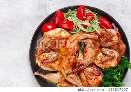 Baked quail, served on a plate with crispy lettuce leaves, fresh tomatoes and herbs, on a dark plate, homemade, 132617907