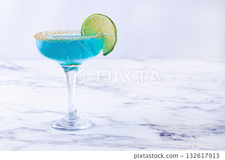 Bright blue cocktail with a slice of lime on a marble surface, 132617913