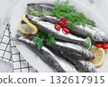 Fresh Herring fish, ready to cook, with herbs and spices, on a white platter, in the kitchen 132617915