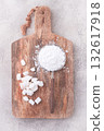 a strainer with powdered sugar, on a wooden cutting board, with pieces of white sugar, 132617918