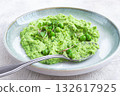 Delicious green pea puree served in a stylish bowl garnished with fresh peas and microgreens for a healthy meal 132617925