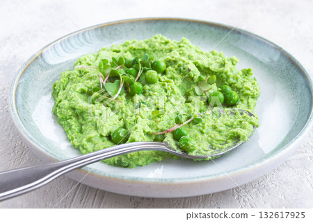 Delicious green pea puree served in a stylish bowl garnished with fresh peas and microgreens for a healthy meal 132617925