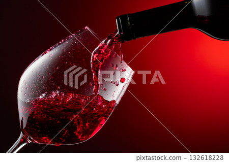 Red wine is poured from a bottle into a glass. 132618228
