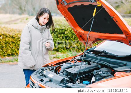 A young female driver who seems to be in trouble because her car breaks down A young female driver who seems to be in trouble because her car breaks down 132618241