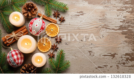 Festive holiday arrangement featuring candles, ornaments, pinecones, and dried oranges on rustic wooden surface, creating a warm seasonal atmosphere 132618328