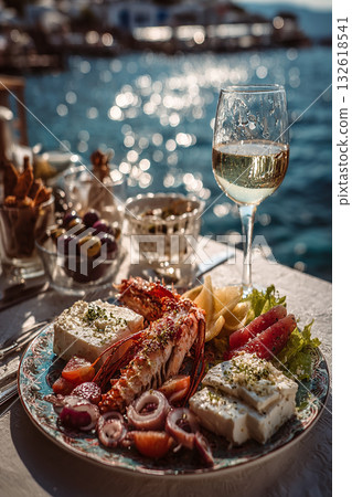 Seafoods, shrimp, appetizers, salads on table. Greek food experience, Aegean seaside dining. Glass white wine, fresh flavors. Vertical Turkish style fish restaurant. Santorini, Turkey, or Greece. Seafoods, shrimp, appetizers, salads on table. Greek food experience, Aegean seaside dining. Glass white wine, fresh flavors. Vertical Turkish style fish restaurant. Santorini, Turkey, or Greece. 132618541