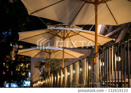Beautiful rows of illuminated parasols and terrace seats at night 132619133
