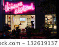 Neon-lit fashion boutiques and silhouettes of passersby at night 132619137