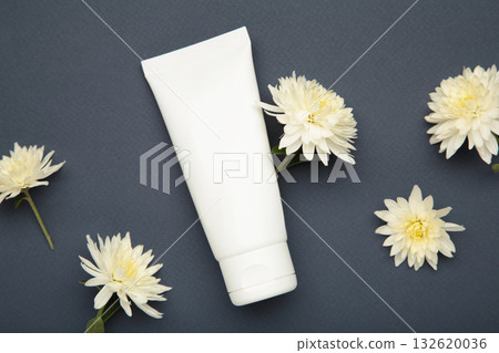 Natural beauty essential. Skincare cream with chrysanthemums on dark blue background Natural beauty essential. Skincare cream with chrysanthemums on dark blue background 132620036