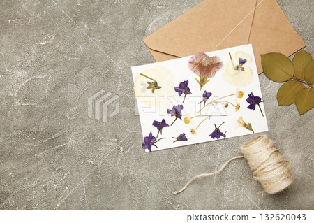 Pressed and dried flowers with twine on grey concrete background. For use in scrapbooking, floristry or herbarium. Pressed and dried flowers with twine on grey concrete background. For use in scrapbooking, floristry or herbarium. 132620043