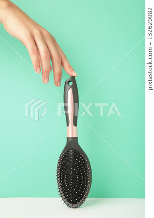 Woman hand holding hairbrush on mint background. Woman hand holding hairbrush on mint background. 132620082