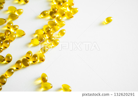 Scattered golden omega capsules on bright white background Scattered golden omega capsules on bright white background 132620291