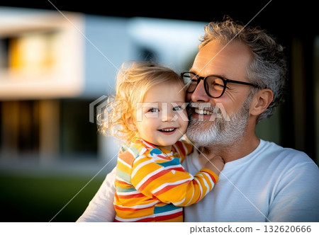A happy grandfather lovingly embraces his granddaughter, sharing a tender moment outdoors 132620666