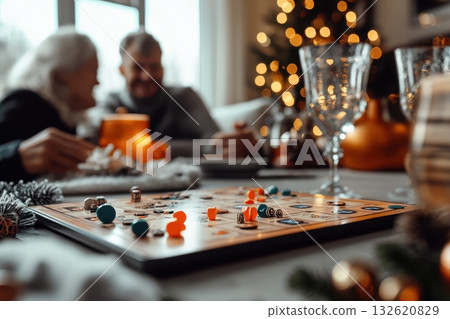 A senior couple plays a board game together during a cozy Christmas gathering, enjoying family time and festive cheer 132620829