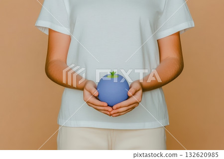A person gently holds a small, blue sphere with a tiny sprout, symbolizing environmental care and growth A person gently holds a small, blue sphere with a tiny sprout, symbolizing environmental care and growth 132620985