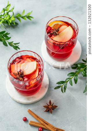 A cranberry drink in a two glasses on a light background with cinnamon and green branch. 132621300
