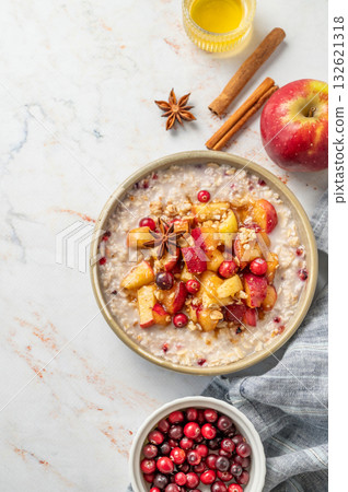 Flat lay of overnight oatmeal with apple, honey, cranberry and cinnamon  on a marble background 132621318
