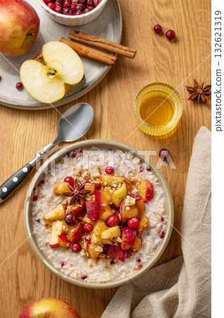 Overnight oatmeal with apple, cranberry and cinnamon in a plate on a wooden background with honey Overnight oatmeal with apple, cranberry and cinnamon in a plate on a wooden background with honey 132621319