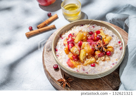 Overnight oatmeal with apple, cranberry and cinnamon in a bowl on a wooden board on blue background Overnight oatmeal with apple, cranberry and cinnamon in a bowl on a wooden board on blue background 132621321