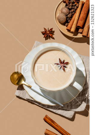 Traditional Indian masala chai tea with milk and spices in a cup on a beige background Traditional Indian masala chai tea with milk and spices in a cup on a beige background 132621323