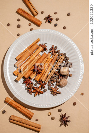 Various spices on a plate against a bright beige background with shadows. Various spices on a plate against a bright beige background with shadows. 132621329