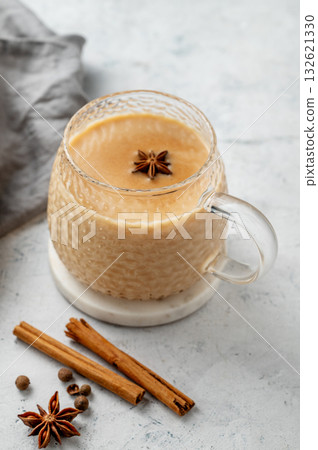 Traditional Indian masala chai tea with milk and spices in a cup on a light background with cinnamon Traditional Indian masala chai tea with milk and spices in a cup on a light background with cinnamon 132621330