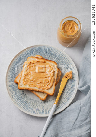 Peanut butter toast on a plate on a light background with napkin and knife. Peanut butter toast on a plate on a light background with napkin and knife. 132621341