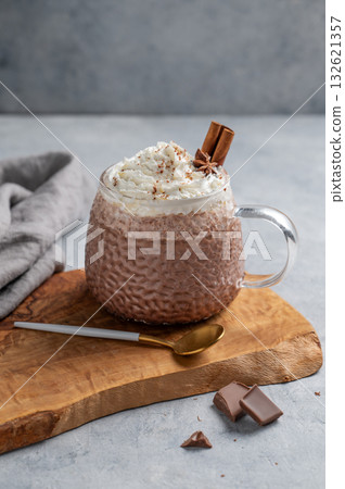 Hot chocolate in a cup with whipped cream and spices on a wooden board on a light background 132621357