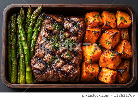 Modern lunch container. Paleo lunch box. Featuring grilled steak, roasted sweet potatoes, and steamed asparagus. Packed in a wooden container. Modern lunch container. Paleo lunch box. Featuring grilled steak, roasted sweet potatoes, and steamed asparagus. Packed in a wooden container. 132621769