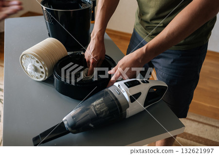 Cropped shot of cleaning company worker wiping interior components of air humidifier, vacuum cleaner positioned nearby for thorough dust removal. Concept of maintenance modern home appliance. Cropped shot of cleaning company worker wiping interior components of air humidifier, vacuum cleaner positioned nearby for thorough dust removal. Concept of maintenance modern home appliance. 132621997