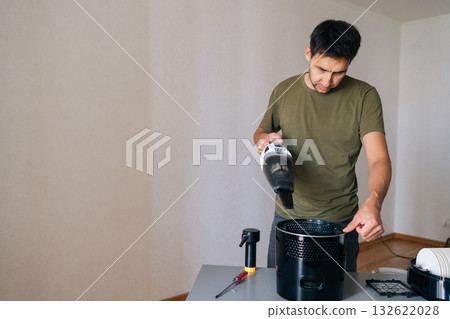 Portrait of cleaning company worker male cleaning air humidifier using handheld vacuum cleaner, performing thorough home device maintenance for optimal indoor air quality and cleanliness. Portrait of cleaning company worker male cleaning air humidifier using handheld vacuum cleaner, performing thorough home device maintenance for optimal indoor air quality and cleanliness. 132622028