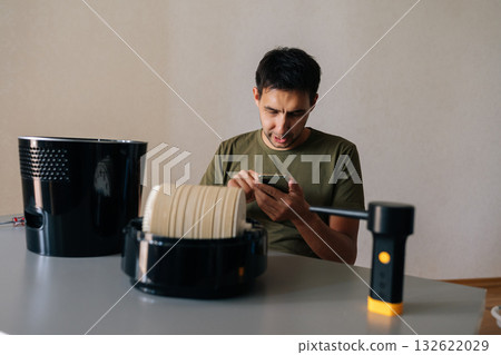 Portrait of skilled technician reading smartphone instructions while cleaning air humidifier filter, focusing on precise maintenance for peak device efficiency. Concept of maintenance home appliance. 132622029