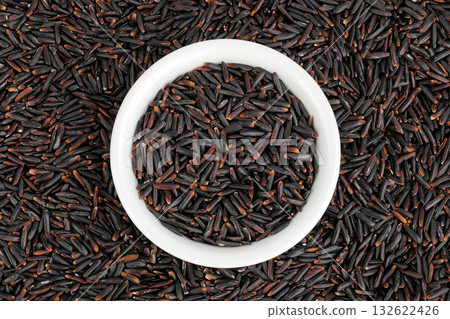 Black rice in a ceramic bowl as a background. Top view. Flat lay 132622426