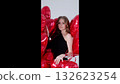 Elegant woman standing amidst bright red heart shaped balloons, radiating romantic mood and celebration spirit for valentine's day or special event 132623254