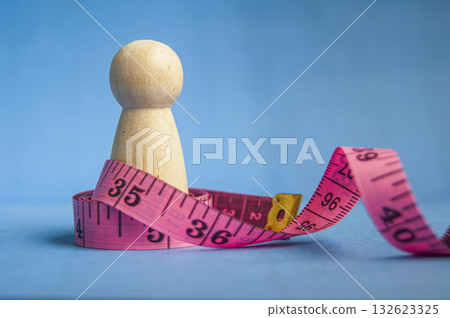 Wooden peg beside pink measuring tape showing healthy lifestyle theme with customizable space for text or ideas. 132623325